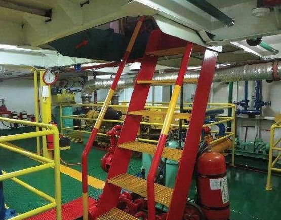 Engine room of a THS vessel with a red ladder, yellow safety railings, and a fire extinguisher